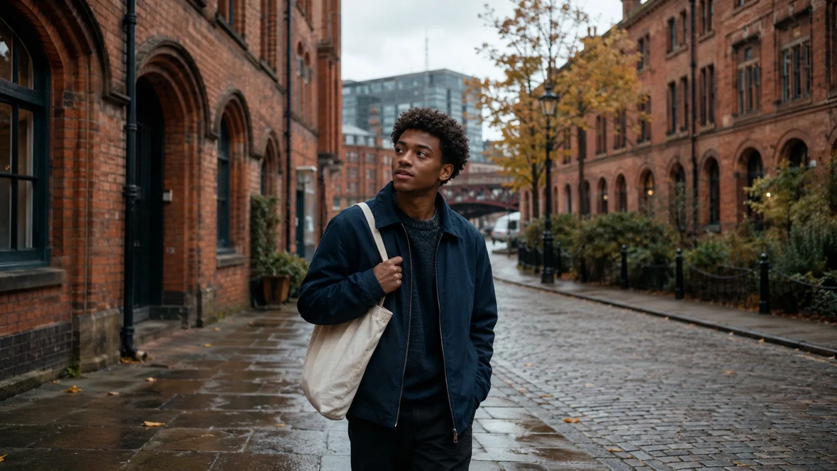 A student walking past red-brick Victorian warehouses in Manchester's Castlefield district in autumn, wet cobbles, slate-grey sky