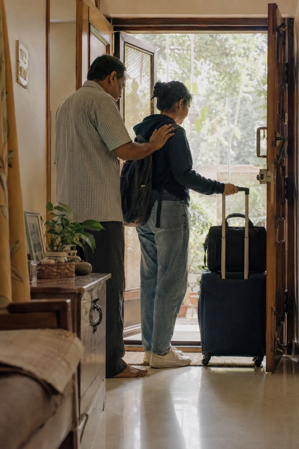 A student and their parent at the front door of home, suitcase ready, the moment before leaving for the UK